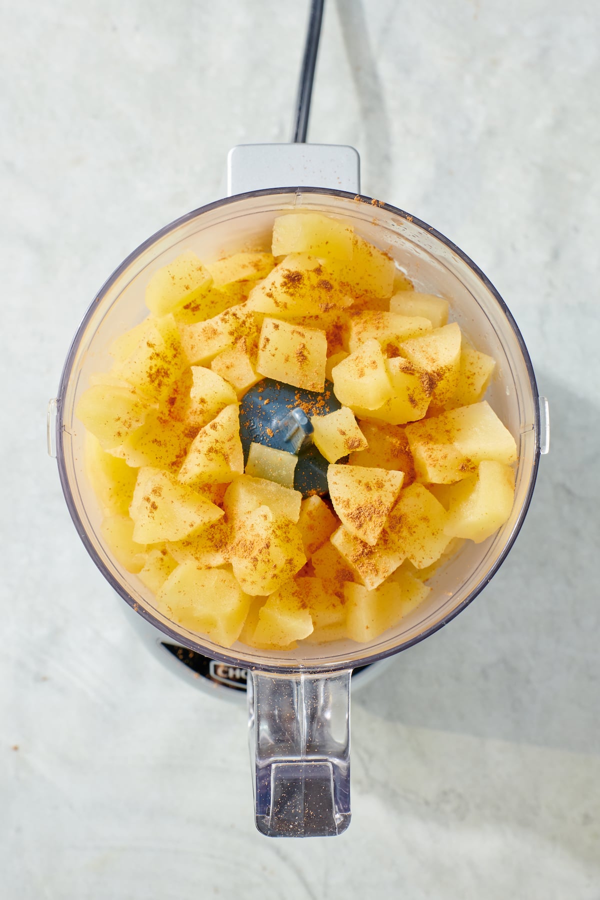 Steamed apples and cinnamon in food processor.