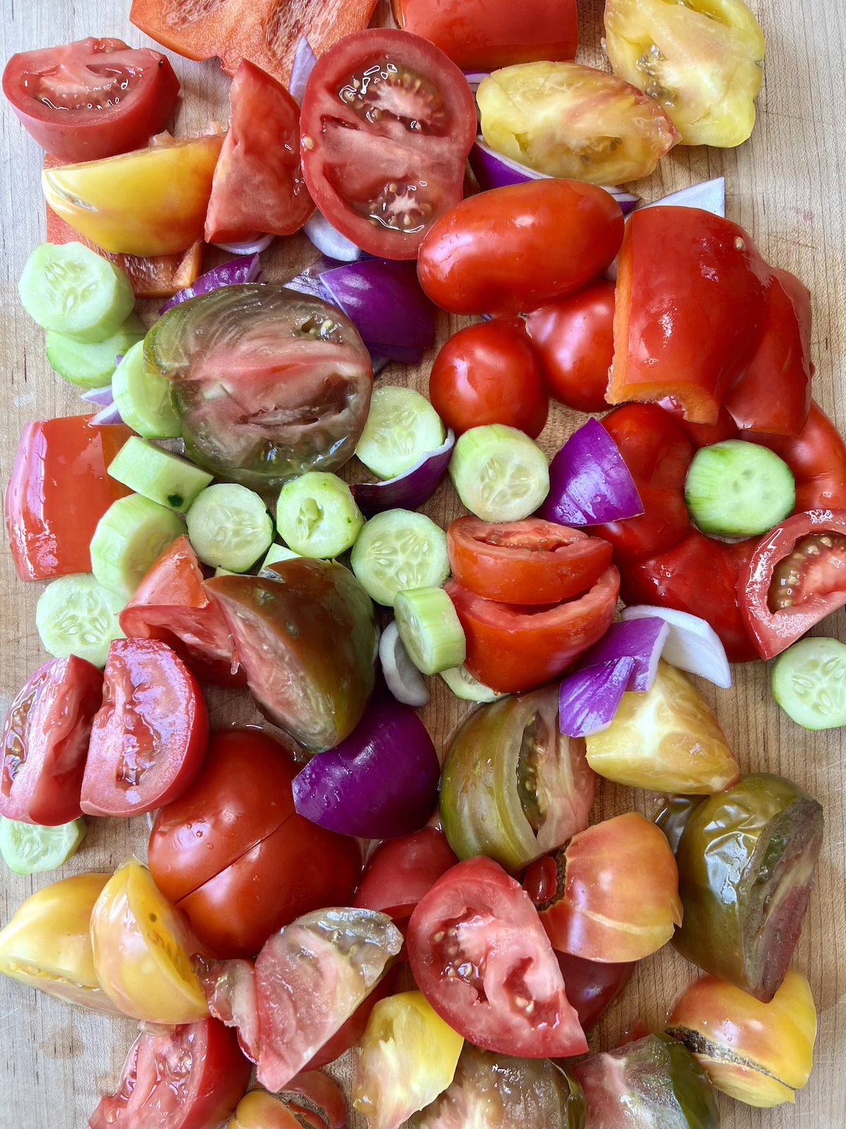 Chopped gazpacho ingredients on cutting board.
