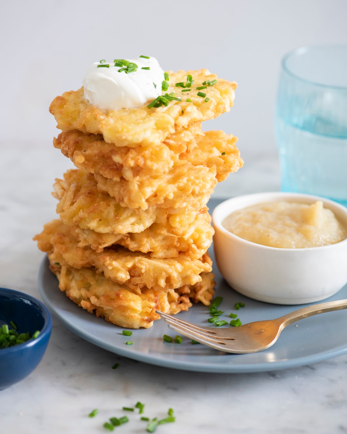 A stack of latkes with dollop of sour cream on top.