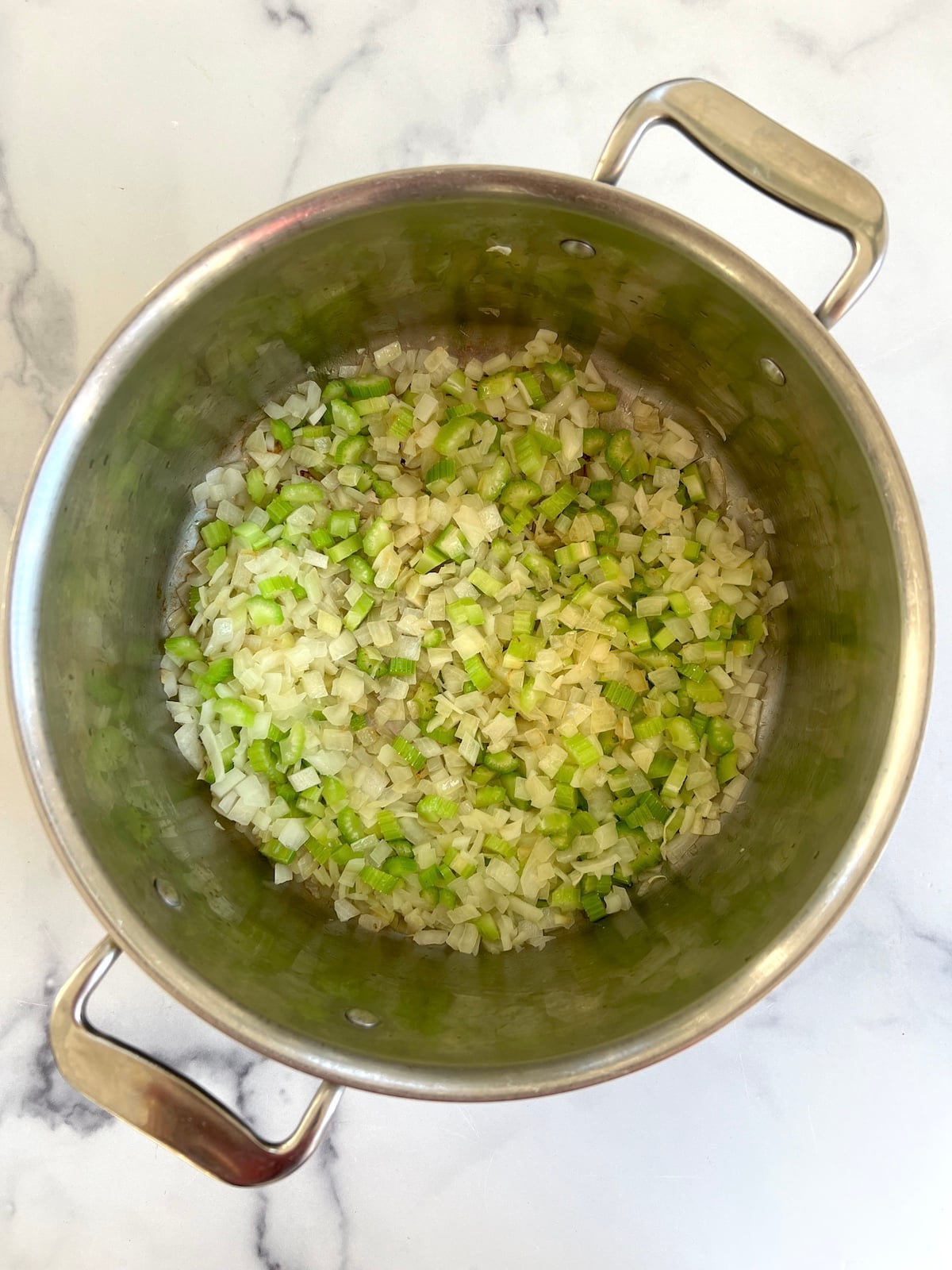 Sautéed onions and celery in a pot.