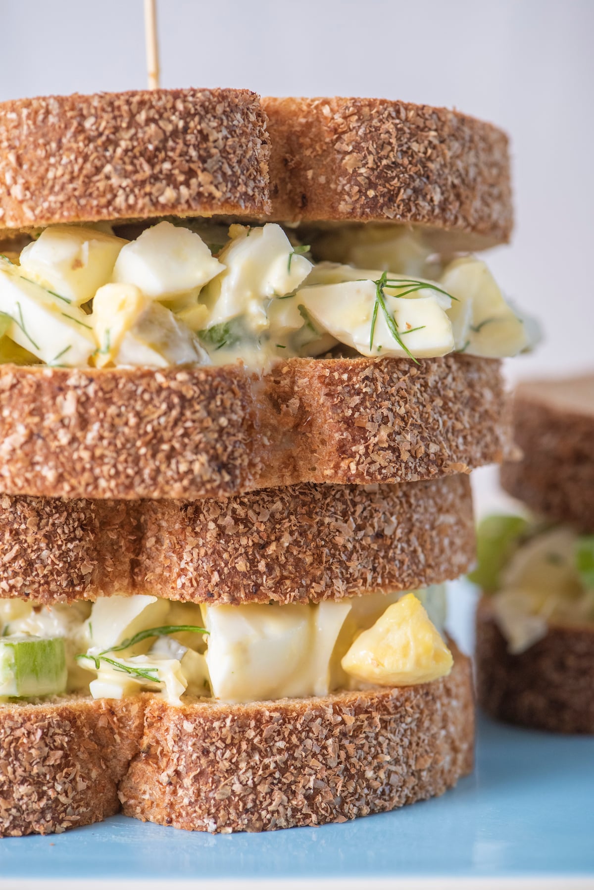 Two egg salad sandwiches stacked on top of each other.