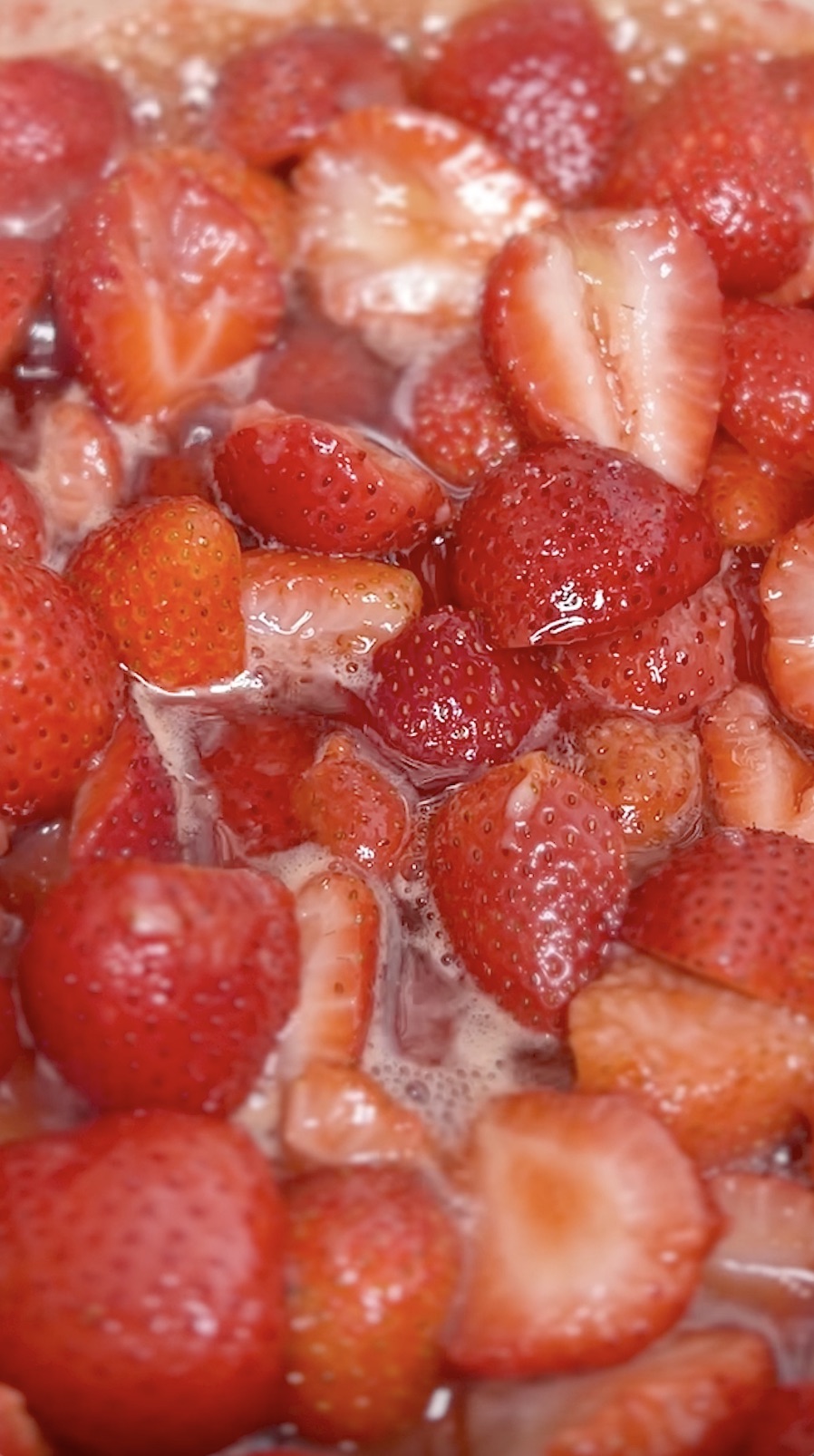 Strawberry preserves cooking in pot.