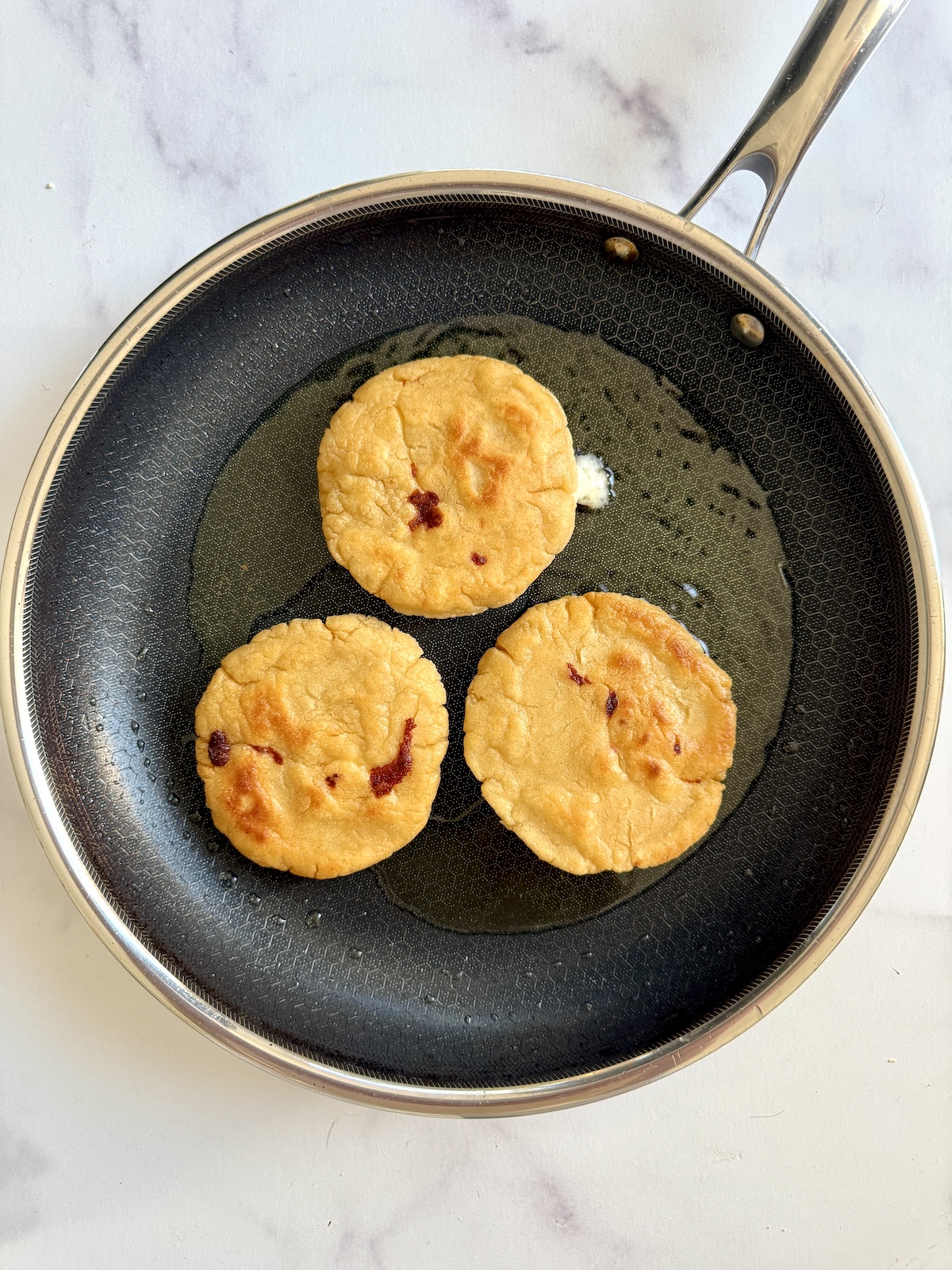 Cooked pupusas on a saute pan.