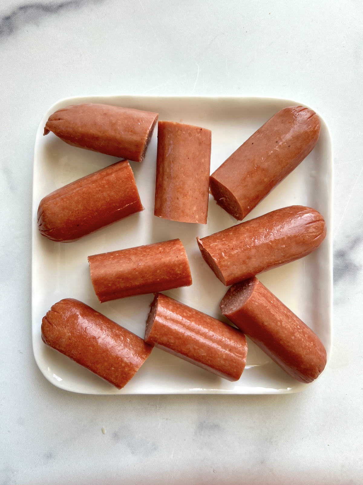 Hot dogs cut into 2 inch pieces on a plate.