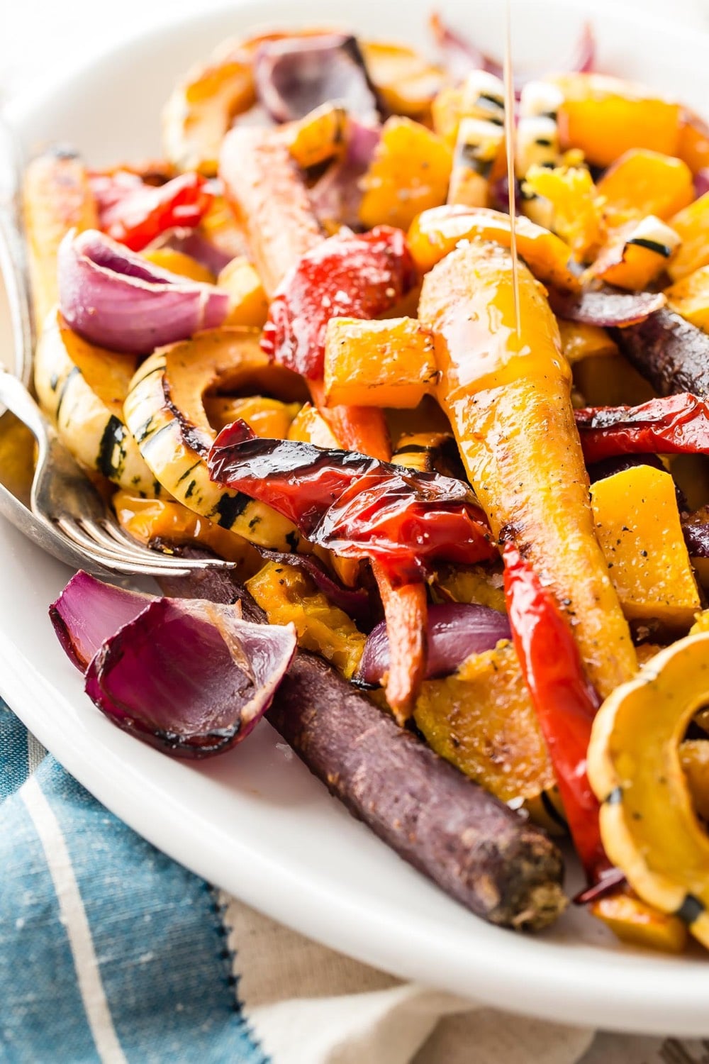 Roast Vegetables being topped with maple syrup.