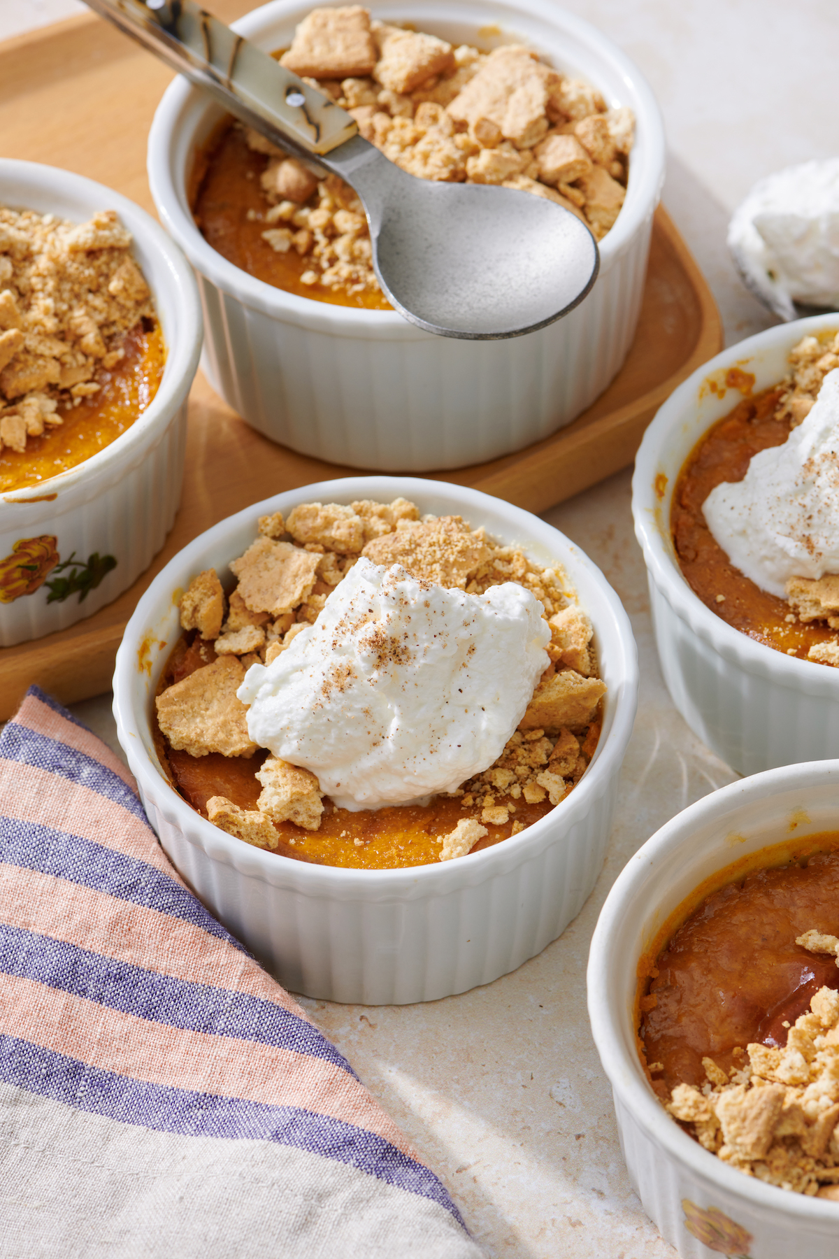 Mini Pumpkin Cheesecakes in individual ramekins. Topped with whipped cream and crushed graham crackers.