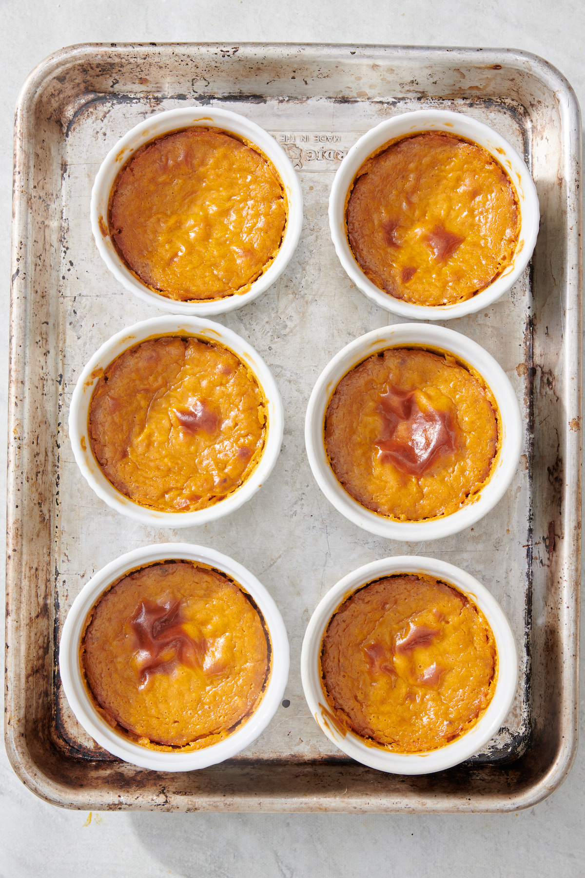 Baked mini pumpkin cheesecakes on baking sheet.