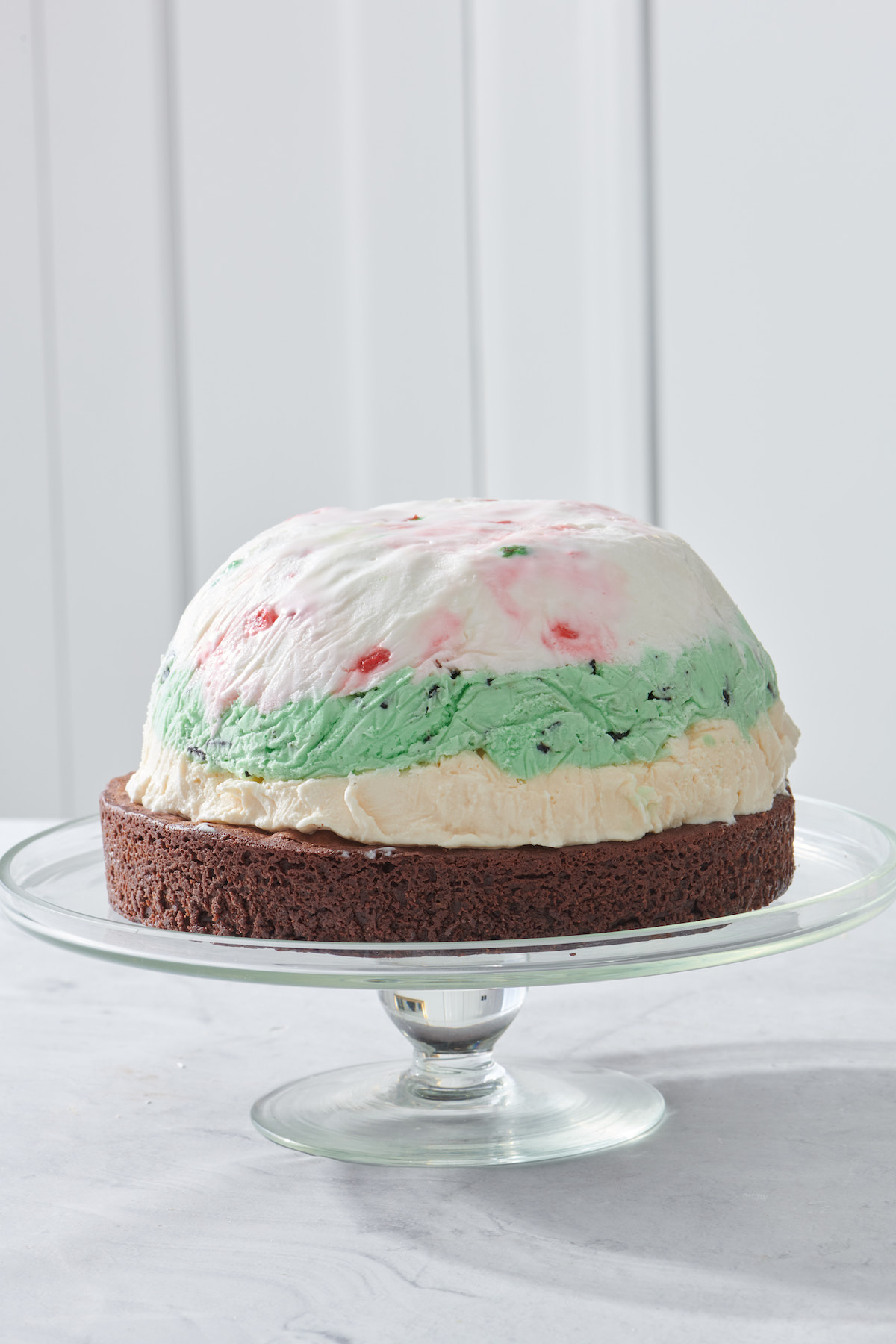 Dome of layered ice cream stacked on top of a brownie base.