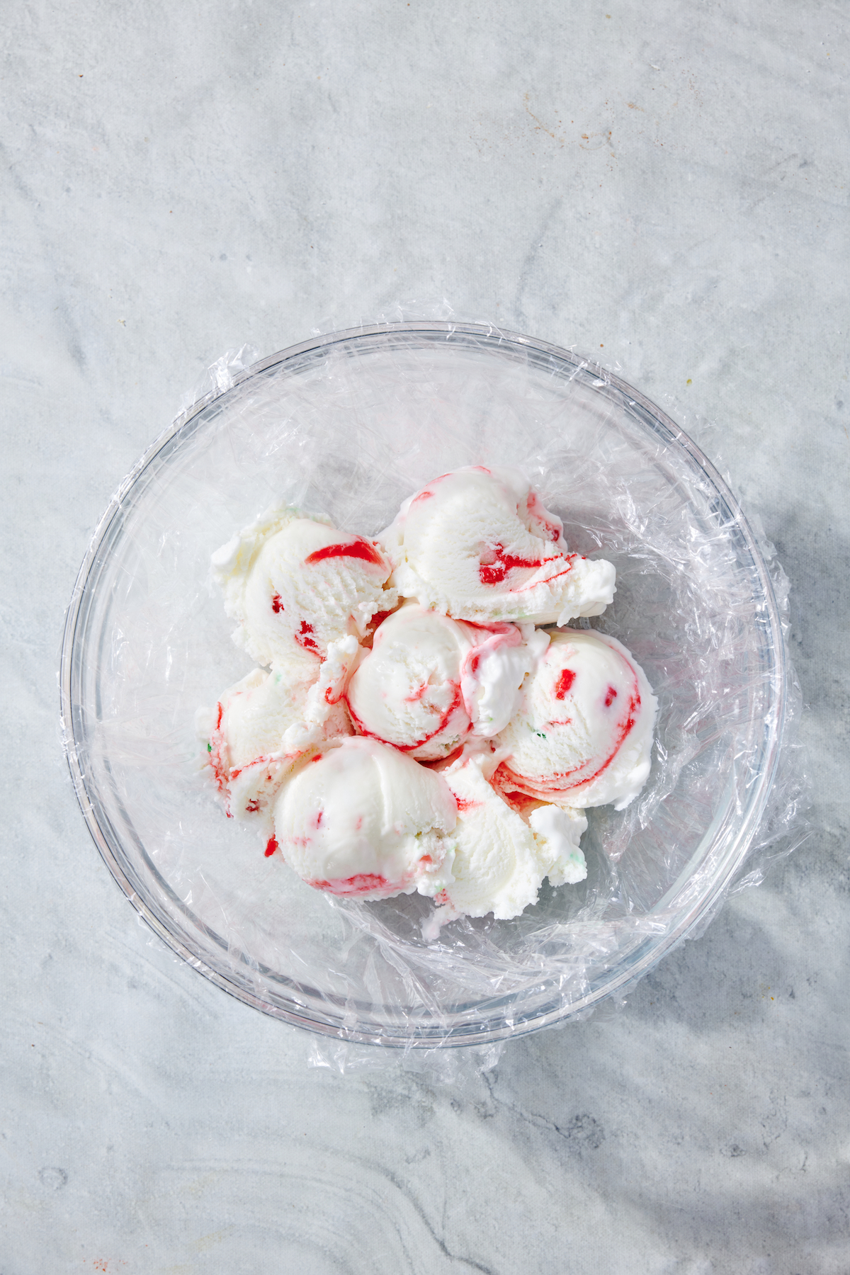 Scoops of peppermint ice cream in a bowl before smoothing into a layer.