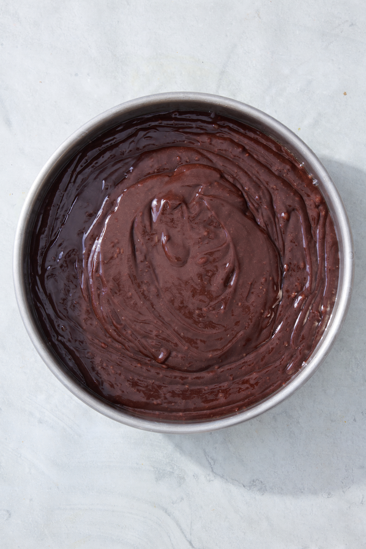 Brownie batter in a cake pan.