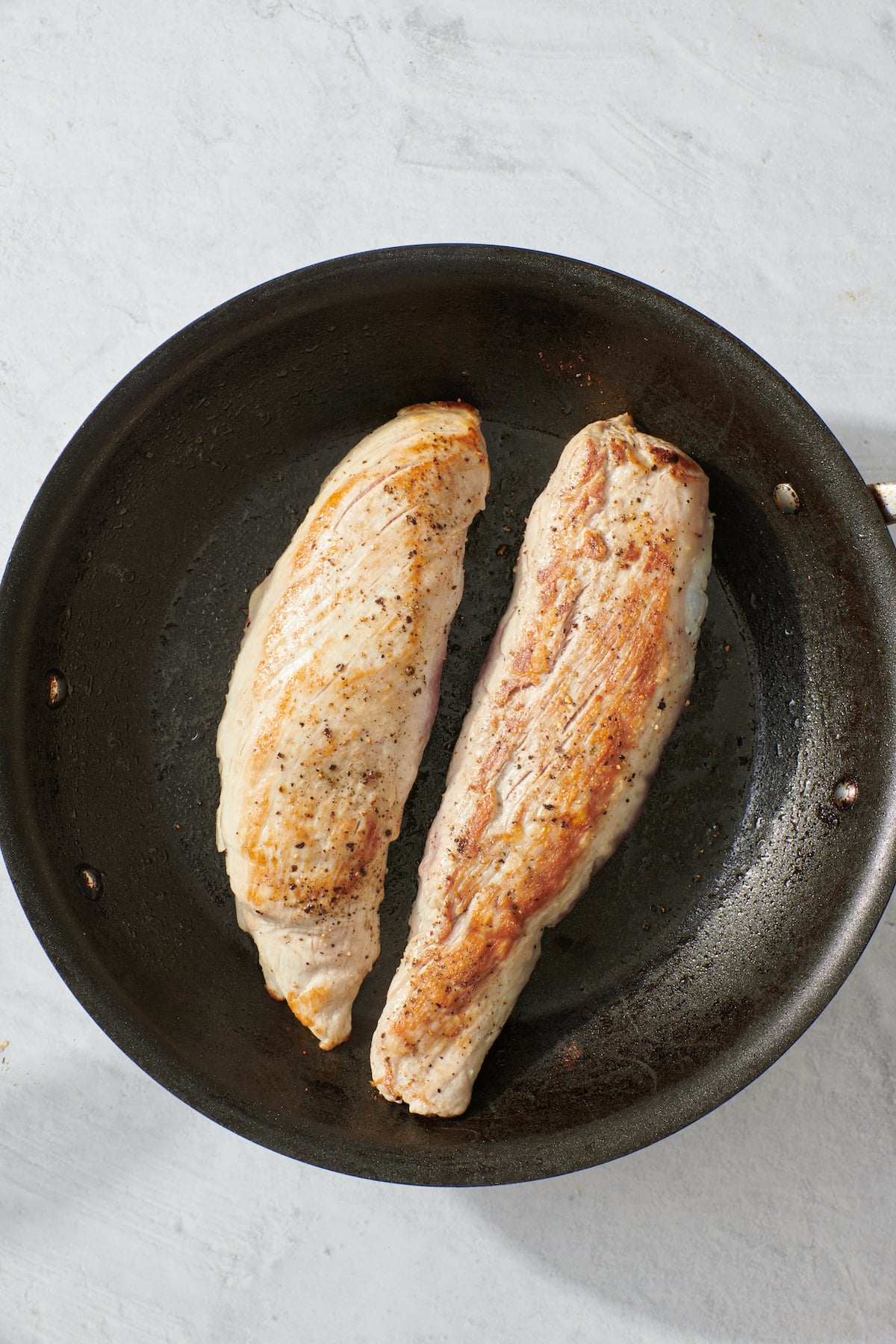 Searing pork tenderloin in sauté pan.