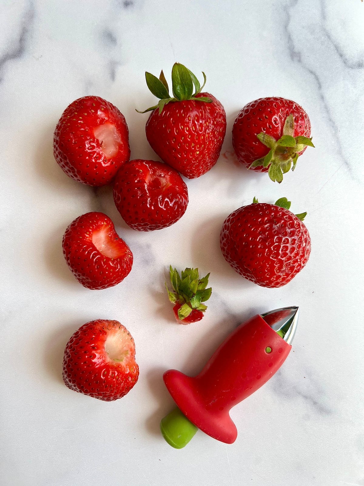 Several strawberries with tops removed using a strawberry huller.