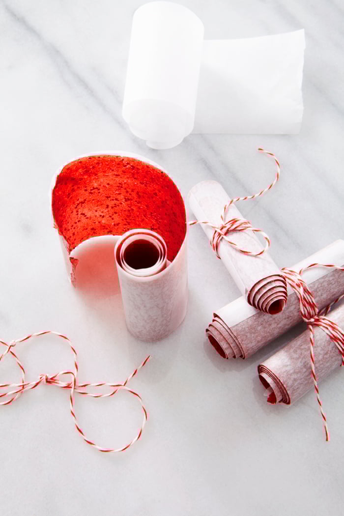 Strawberry fruit leather, rolled up in parchment paper and tied with string.