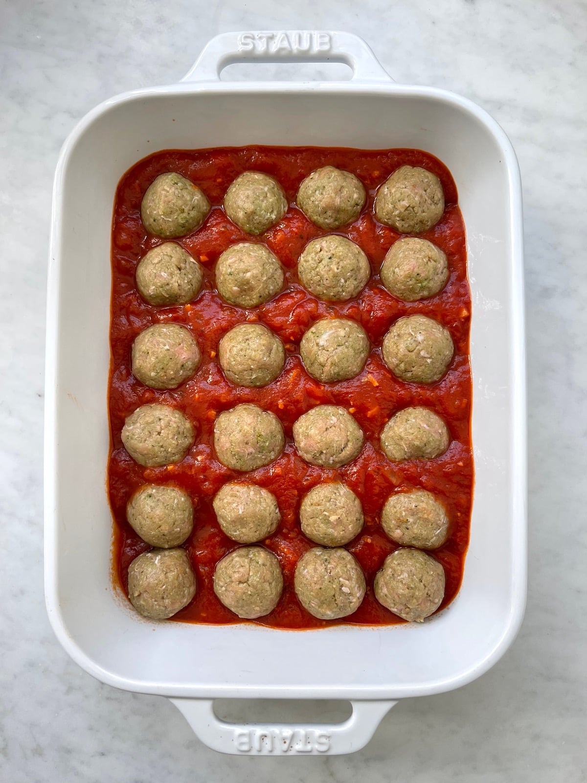 Turkey Pesto Meatballs in baking dish with sauce before cooked.
