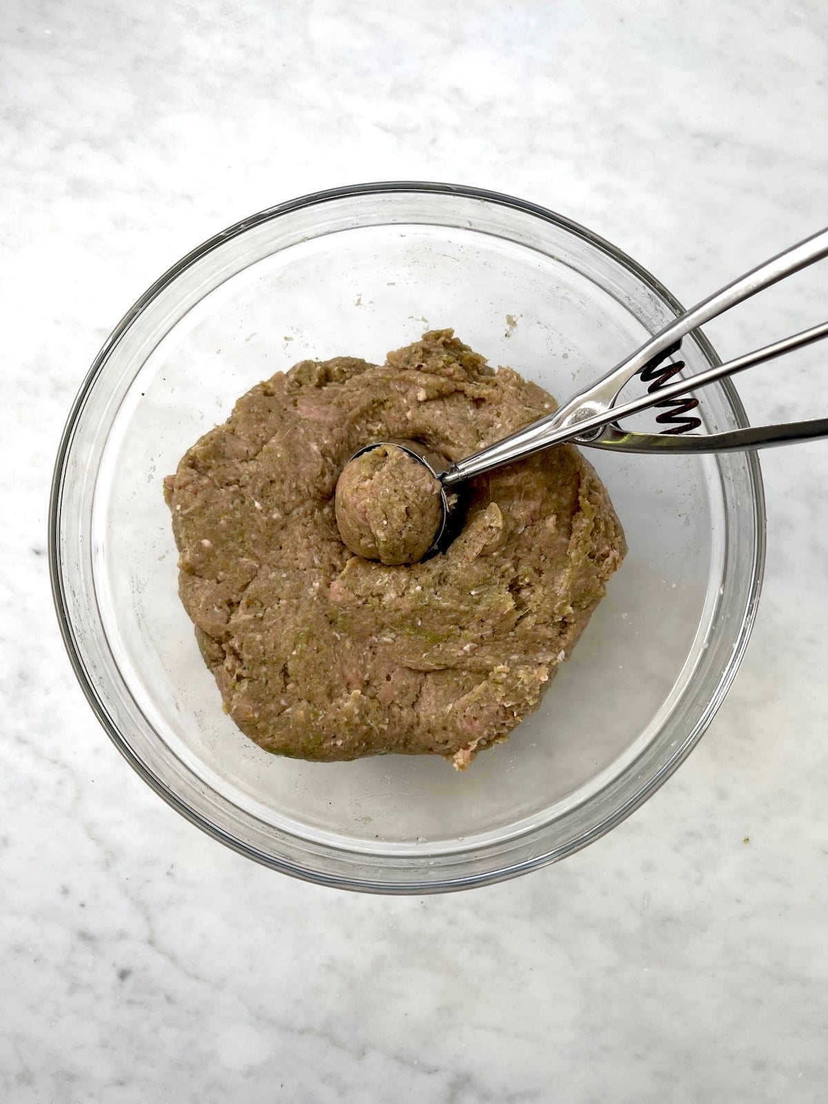 Turkey Pesto Meatball mixture in bowl with scoop.