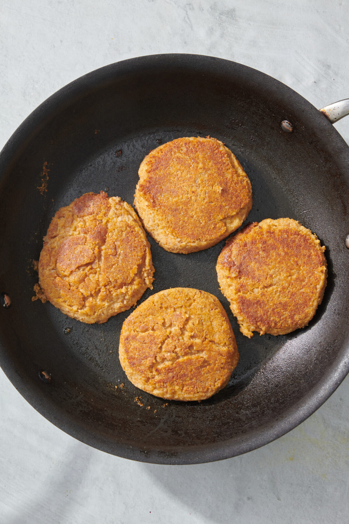 Four veggie burgers in saute pan.