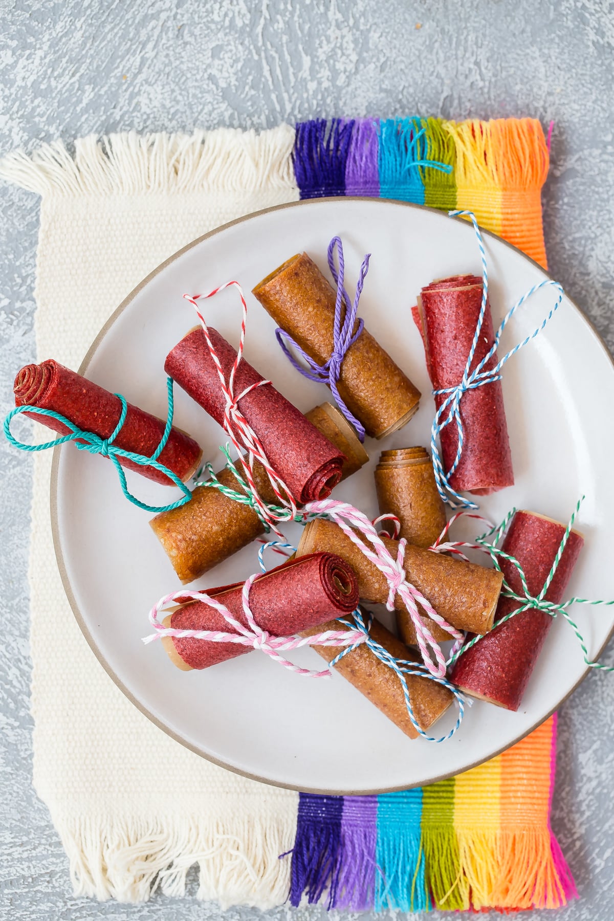 Fruit leather rolled up and tied with string on a plate.