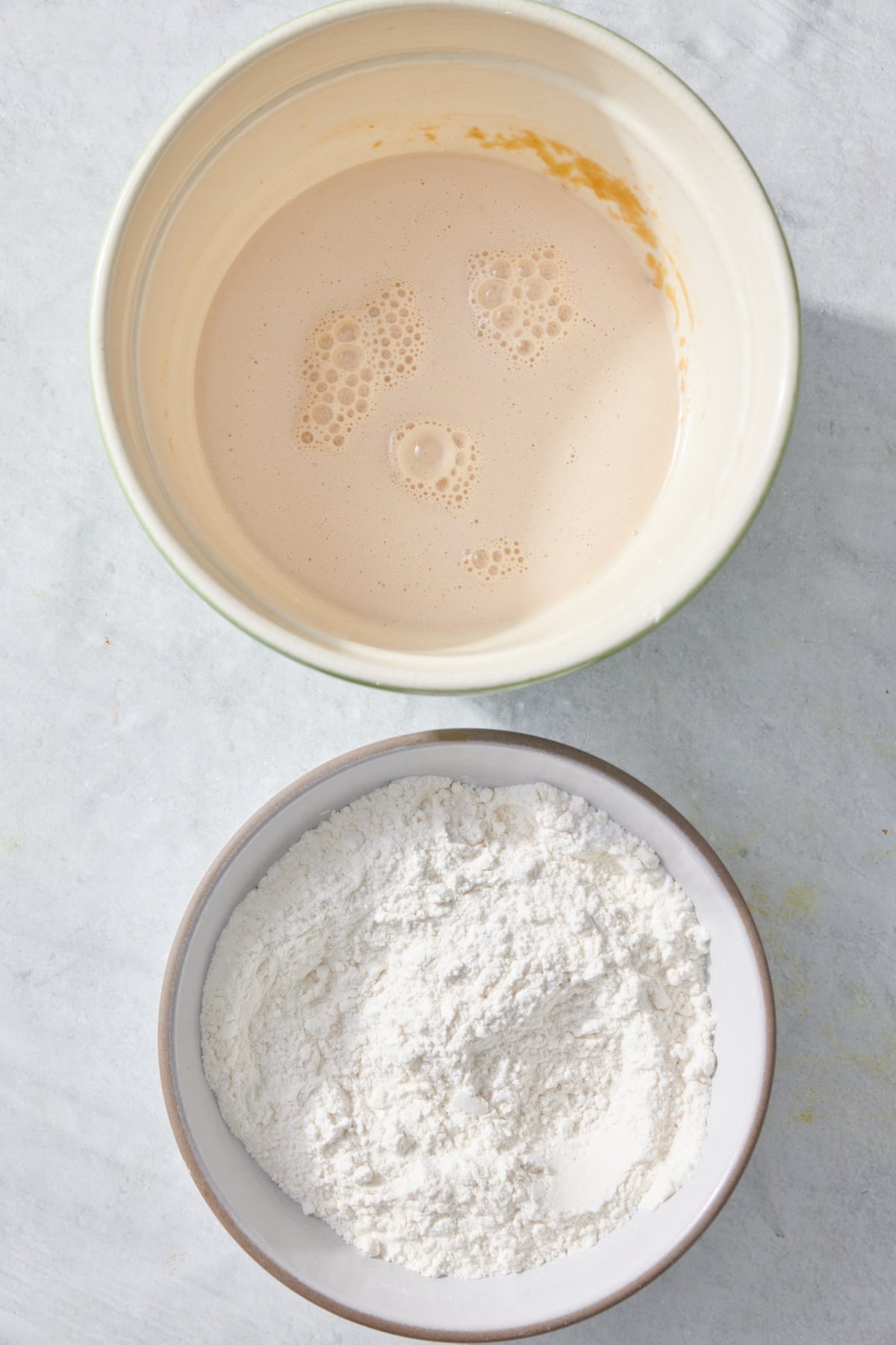 A bowl with combined wet ingredients and a seprate bowl next to it with the combined dry ingredients.