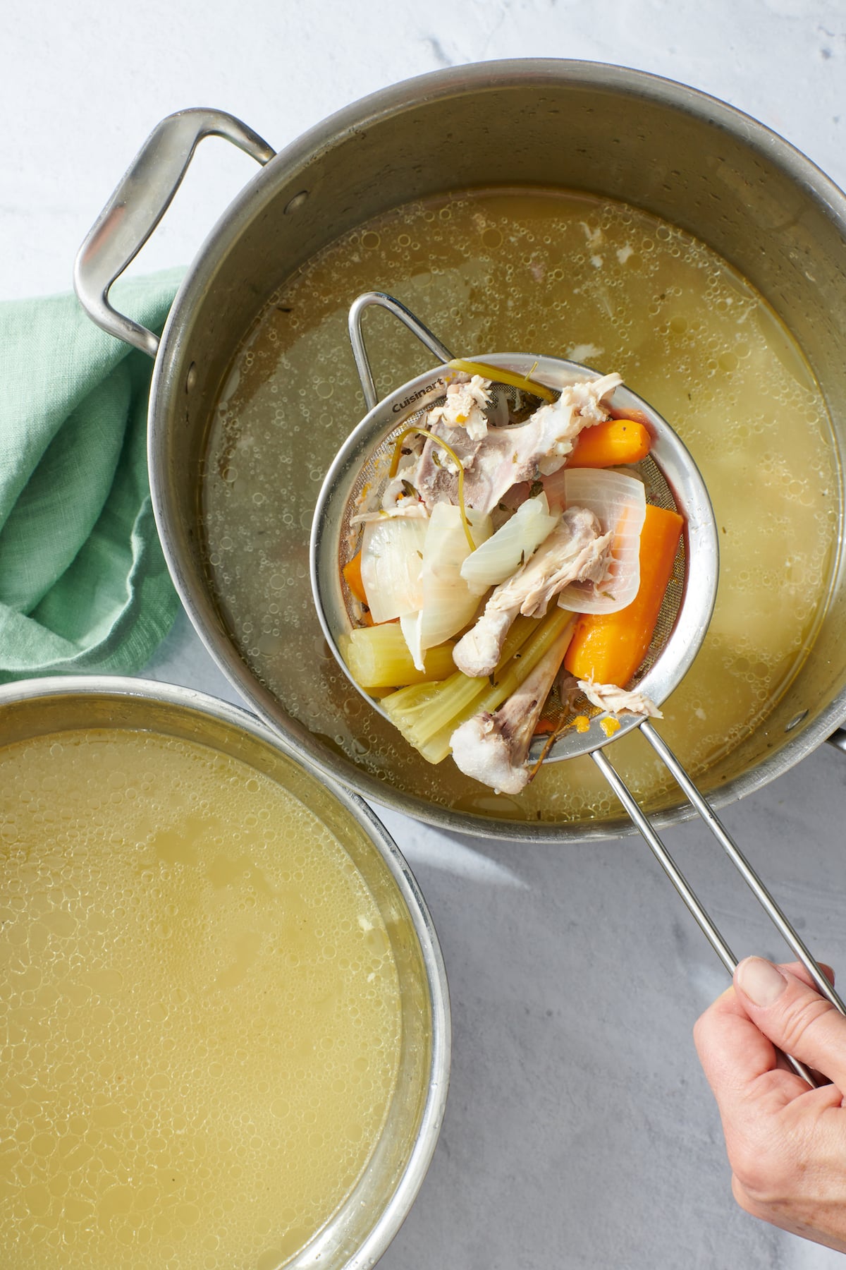 Straining chicken stock into another container.