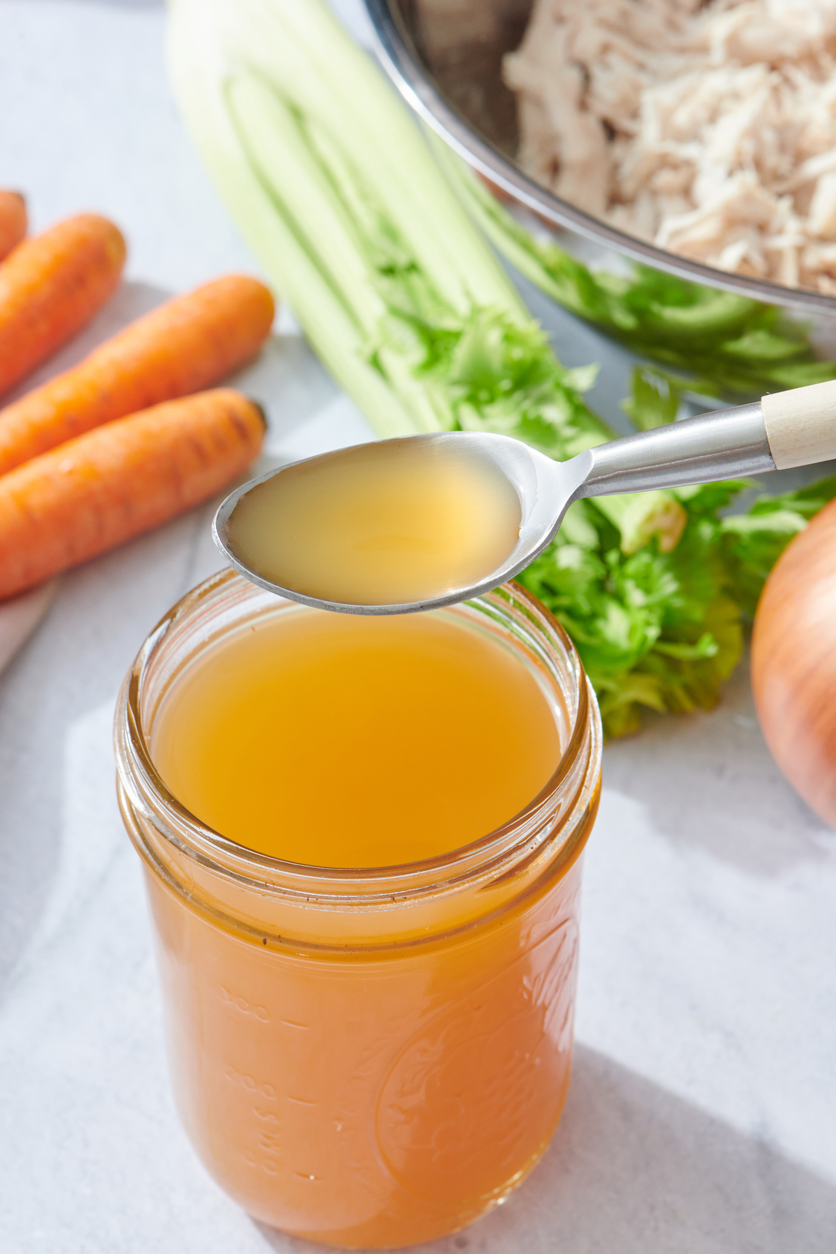 Chicken stock in mason jar with spoonful of stock.