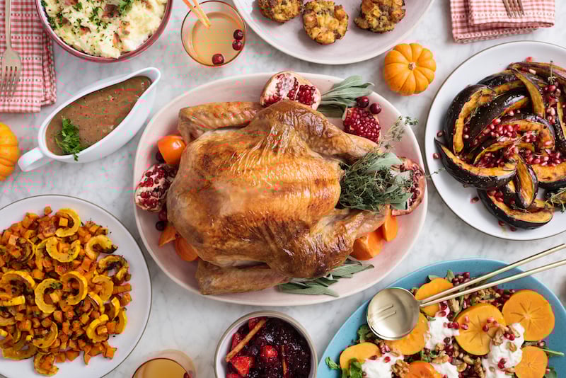 A Thanksgiving turkey in the center of a table with other Thanksgiving dishes.