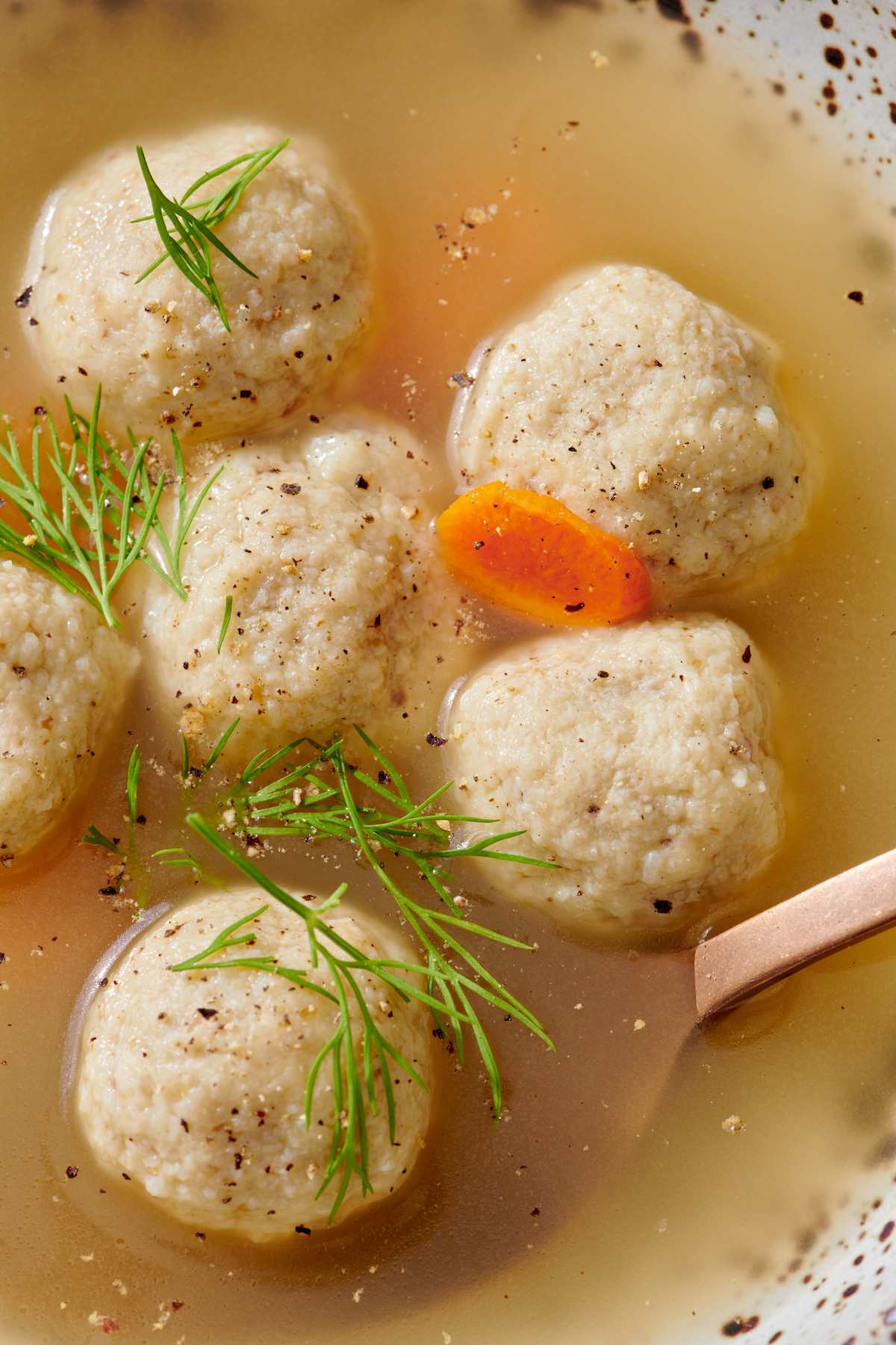 Close up of mini matzah balls in broth.