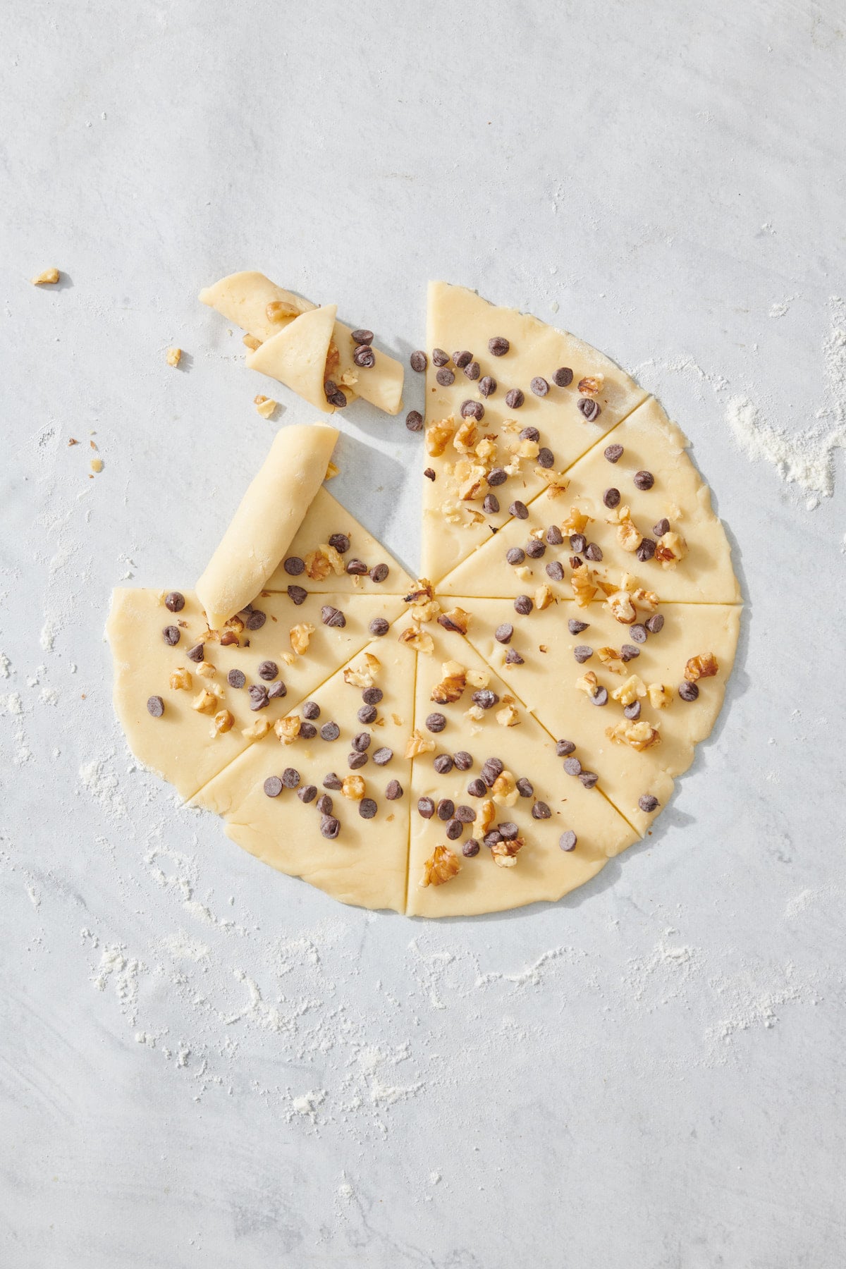 Rolling each wedge into crescent roll shape.