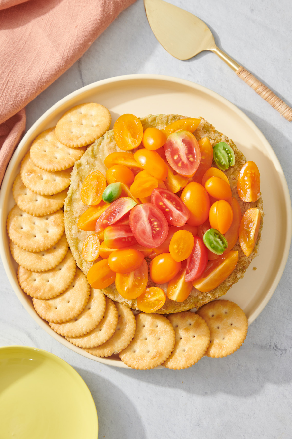 Savory basil pesto cheesecake dip on serving platter with crackers.