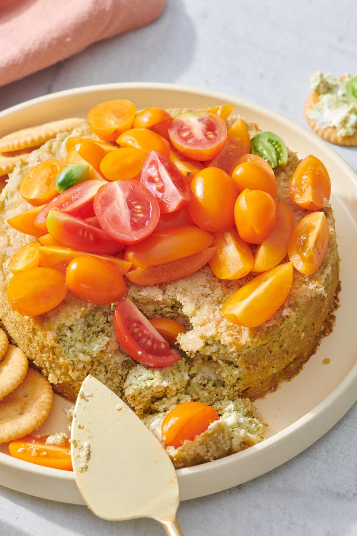 Basil Pesto Cheesecake Dip topped with sliced tomatoes and served with crackers.