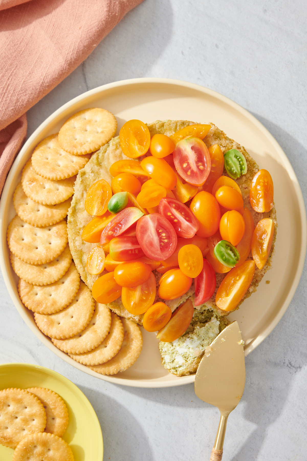 Savory basil pesto cheesecake dip on serving platter with crackers.
