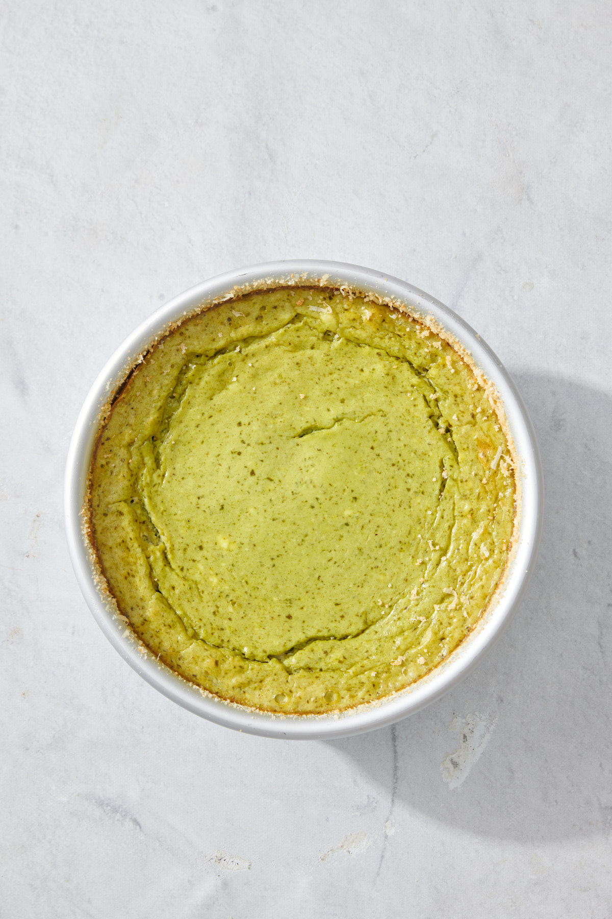 Basil pesto cheesecake dip baked in cake pan.