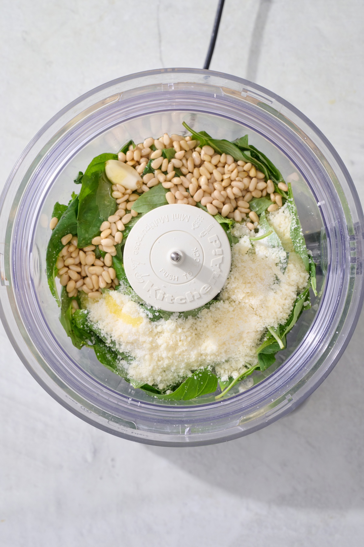 Basil pesto ingredients in food processor bowl.