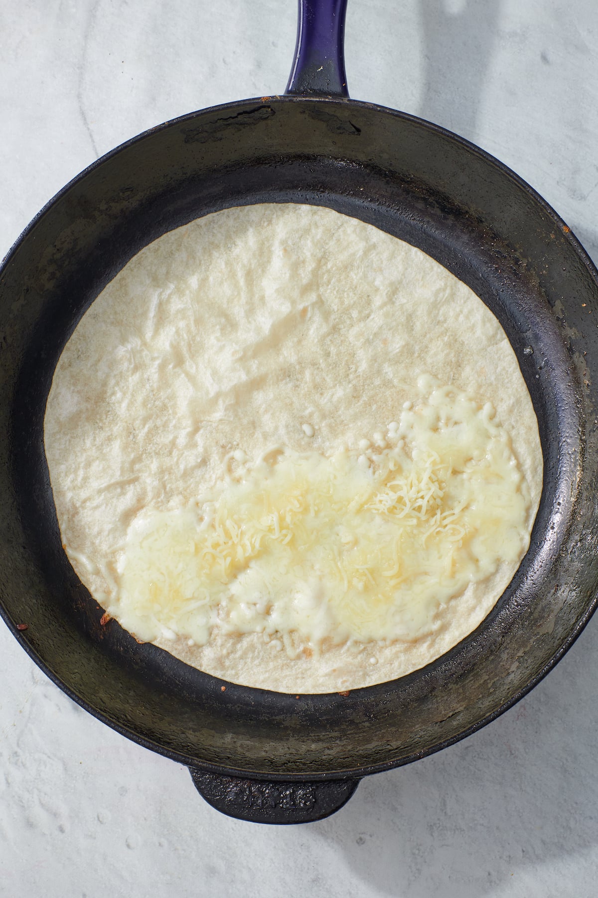 tortilla on frying pan with melted cheese