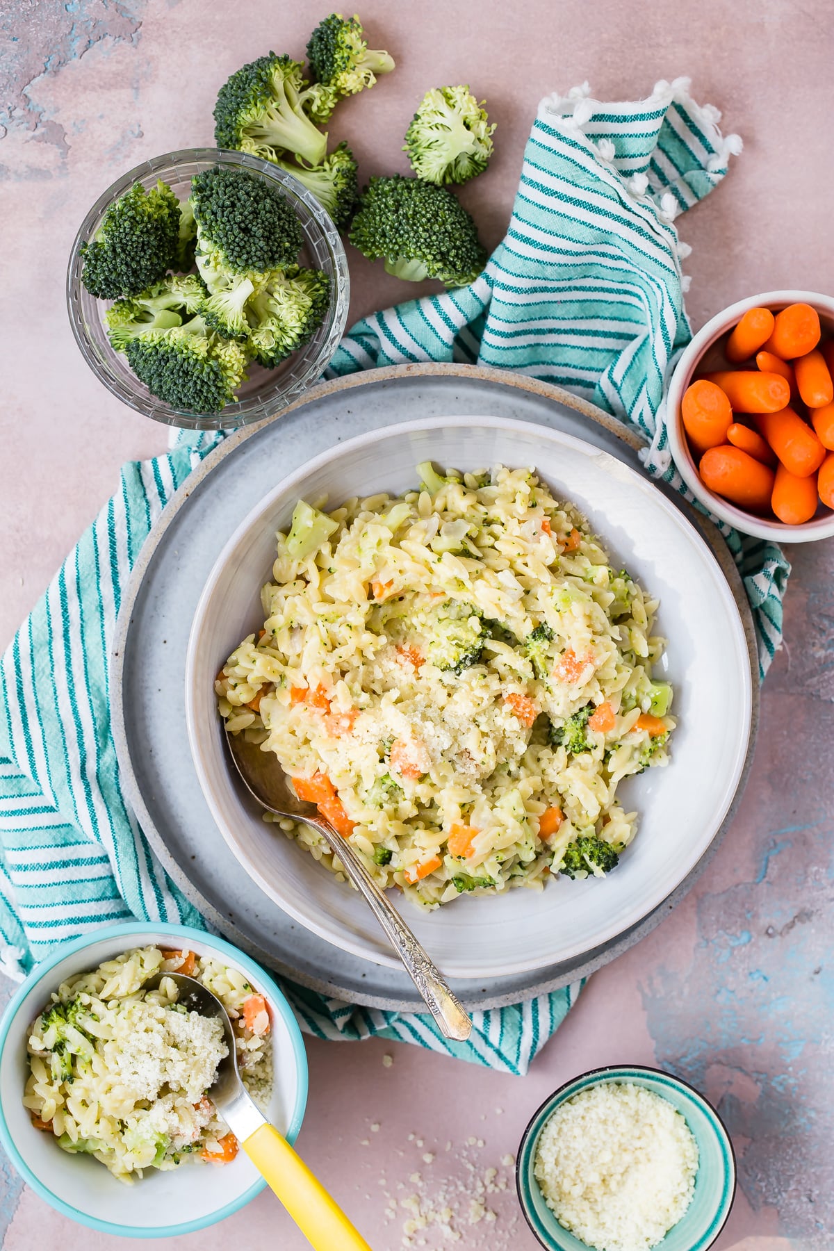 Carrot Broccoli Cheese Orzo in a bowl. Raw broccoli and carrots in bowls next to the orzo dish.