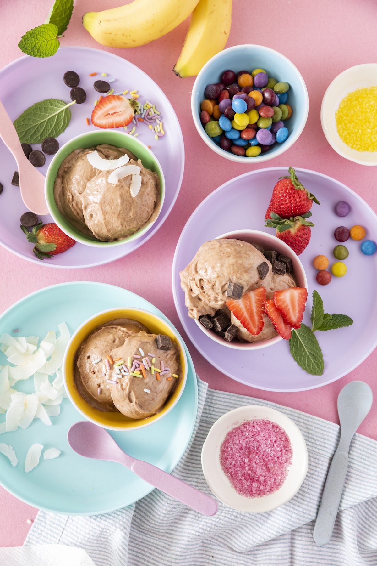 Chocolate banana ice cream served in purple, blue and pink dishes.