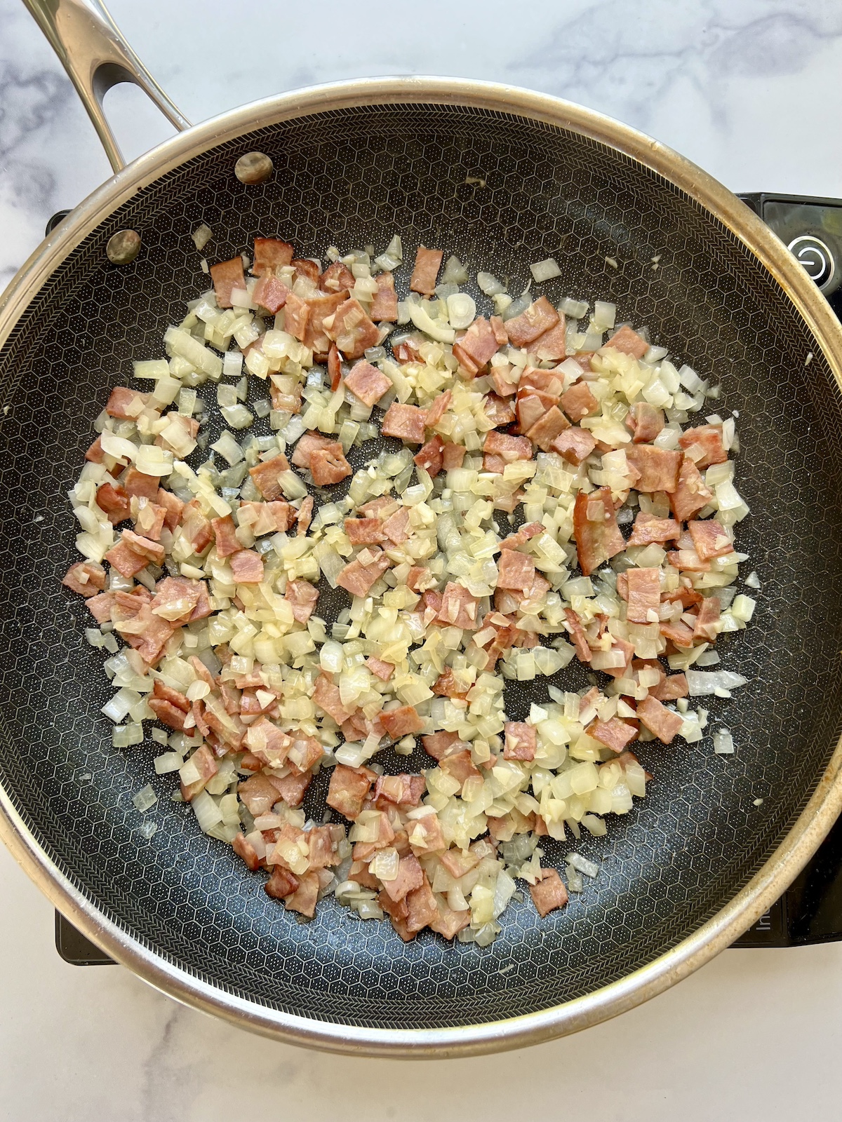 Sautéed onions and chopped turkey bacon in sauté pan.