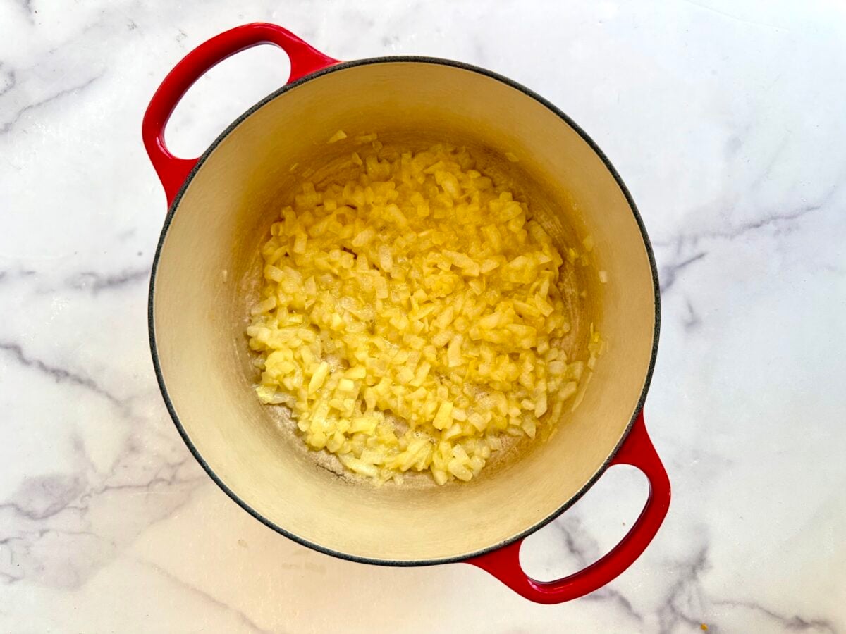 Diced onions and flour sautéing in a red enameled cast iron pot.