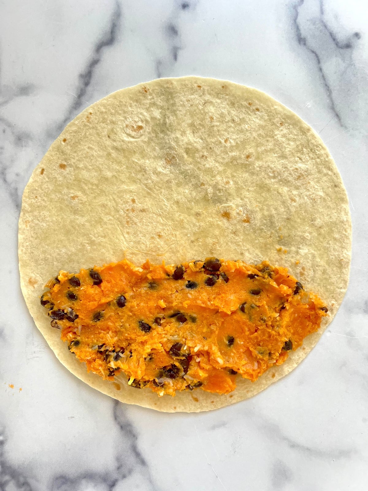 Tortilla with enchilada filling ready to be rolled up.