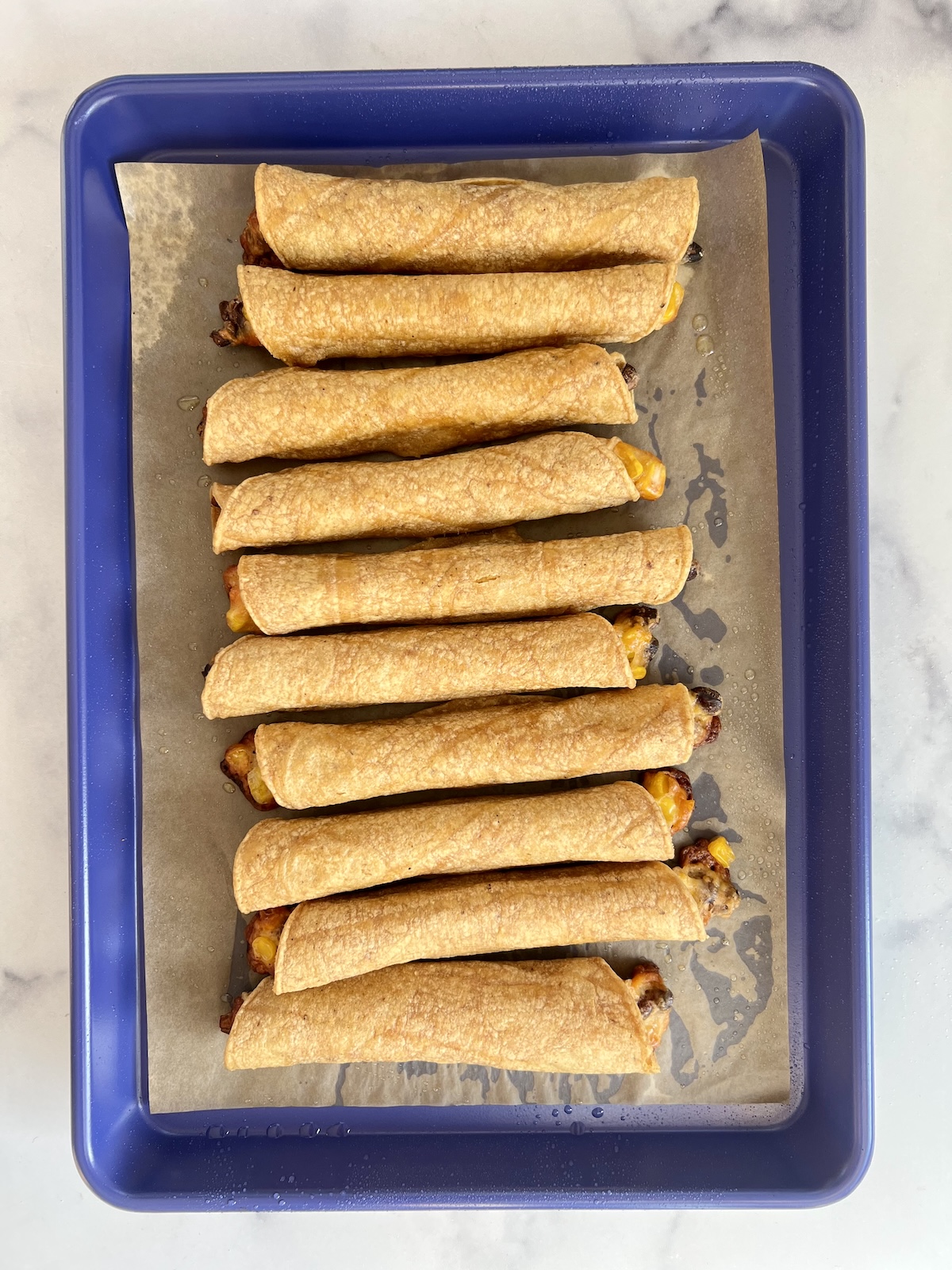 Taquitos on baking sheet ready to be baked.