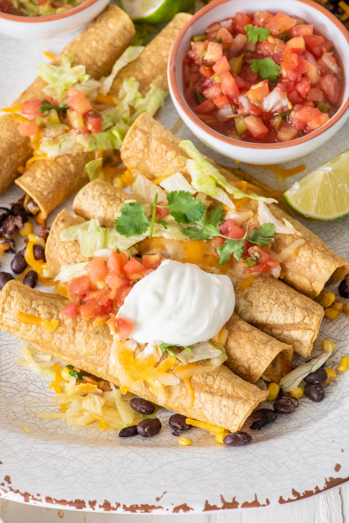 Vegetarian Baked Taquitos topped with pico de gallo and sour cream.