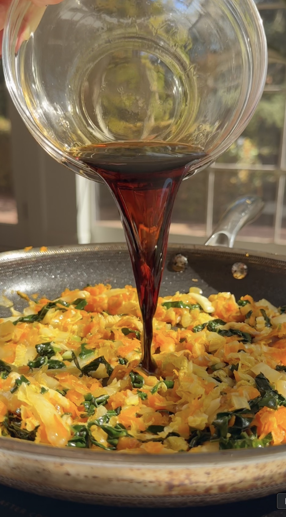 Pouring sauce onto sauteed vegetable mixture.