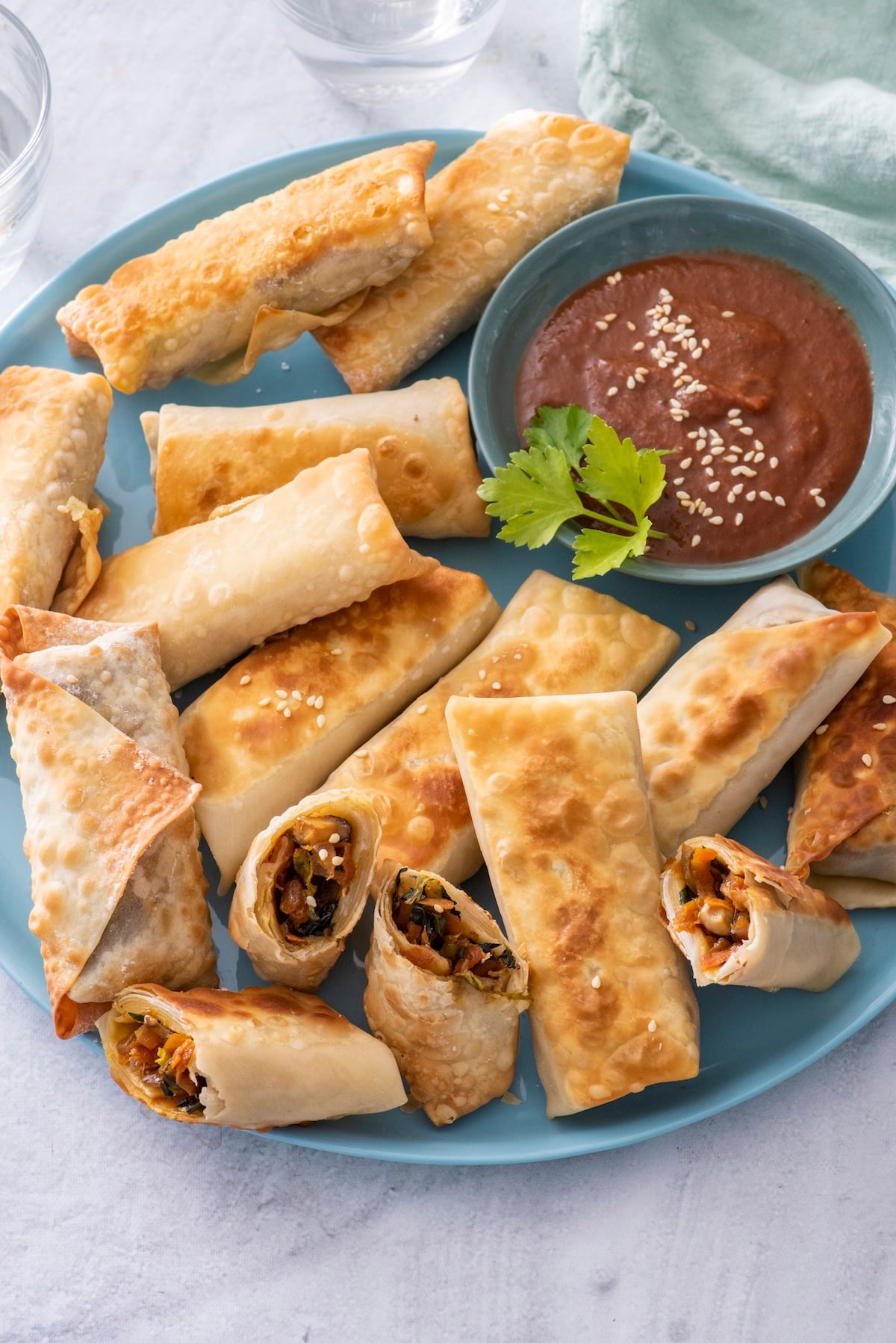 A plate of vegetarian spring rolls with dipping sauce.