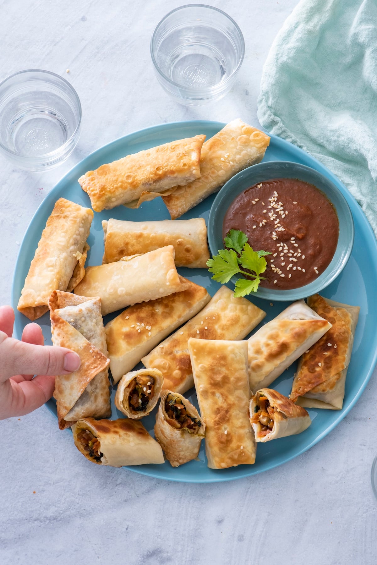Vegetarian spring rolls on a blue plate with dipping sauce.