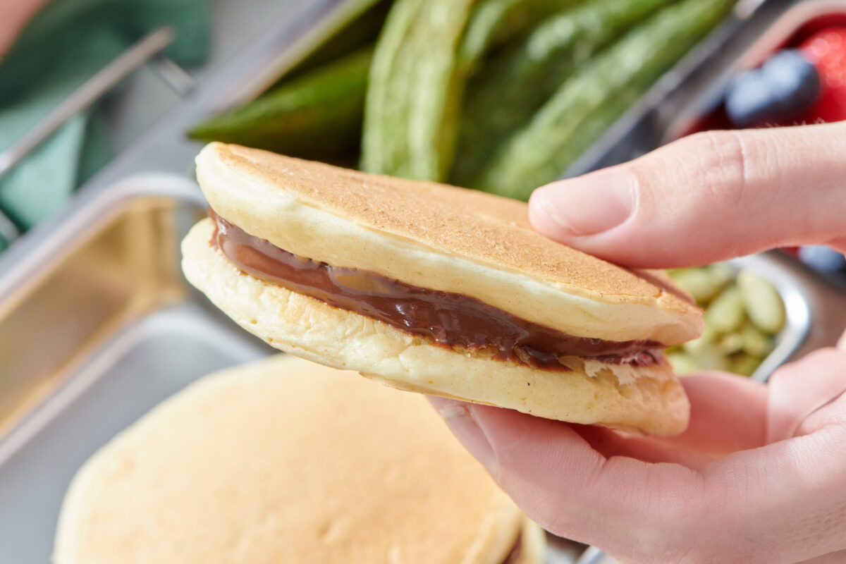 Hand holding chocolate sunbutter pancake sandwich.