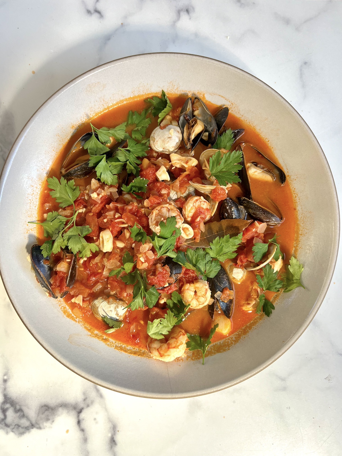 Seafood stew in bowl topped with parsley.
