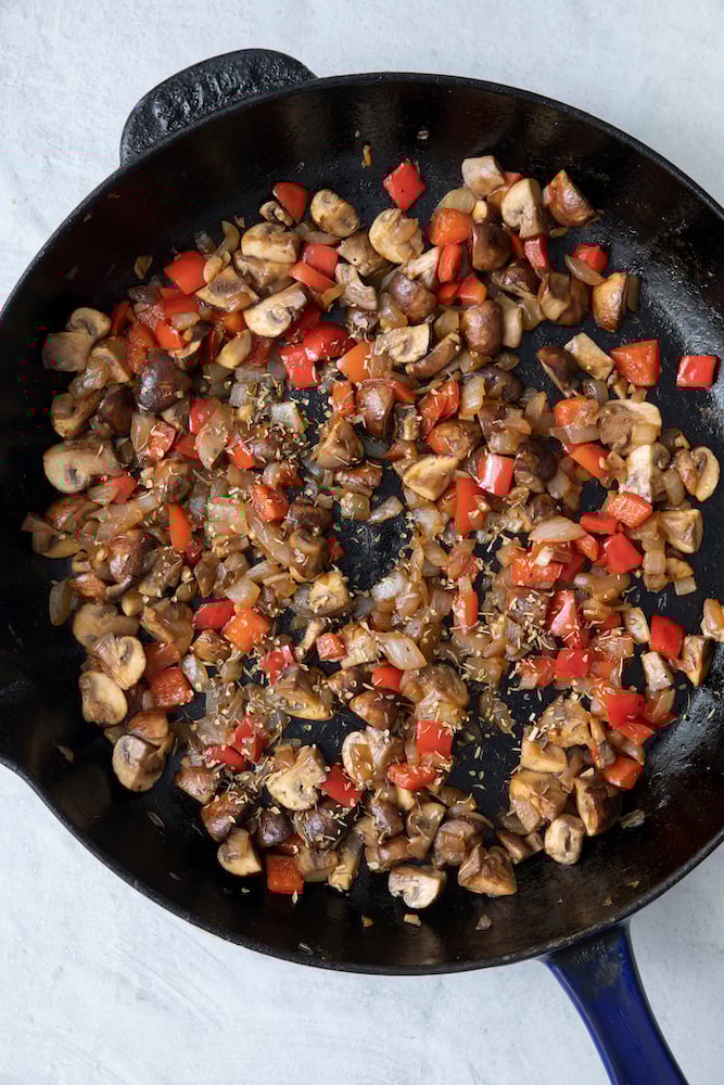 Diced onion, red bell pepper, mushroom sautéed in skillet.