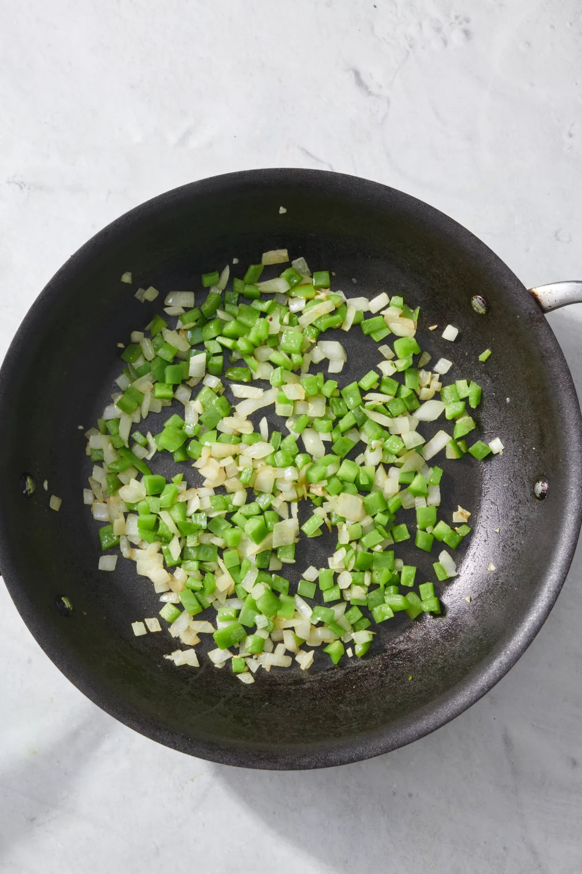 sauteed onions, garlic and green bell peppers in pan