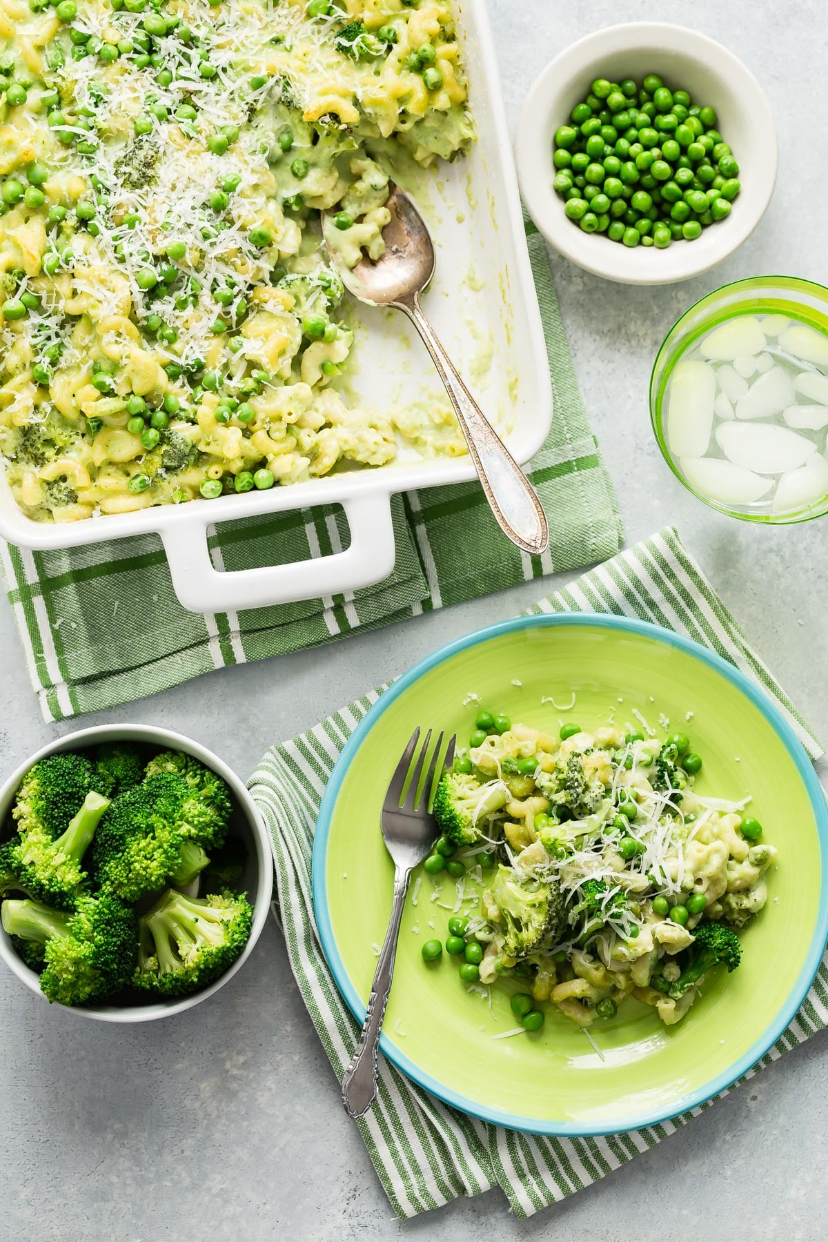 Green Mac and Cheese in a dish with a serving scooped onto a plate.