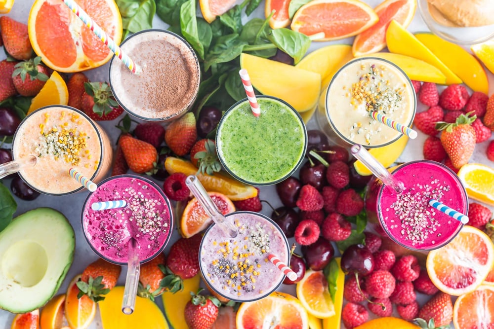 Smoothies surrounded by fresh fruit.