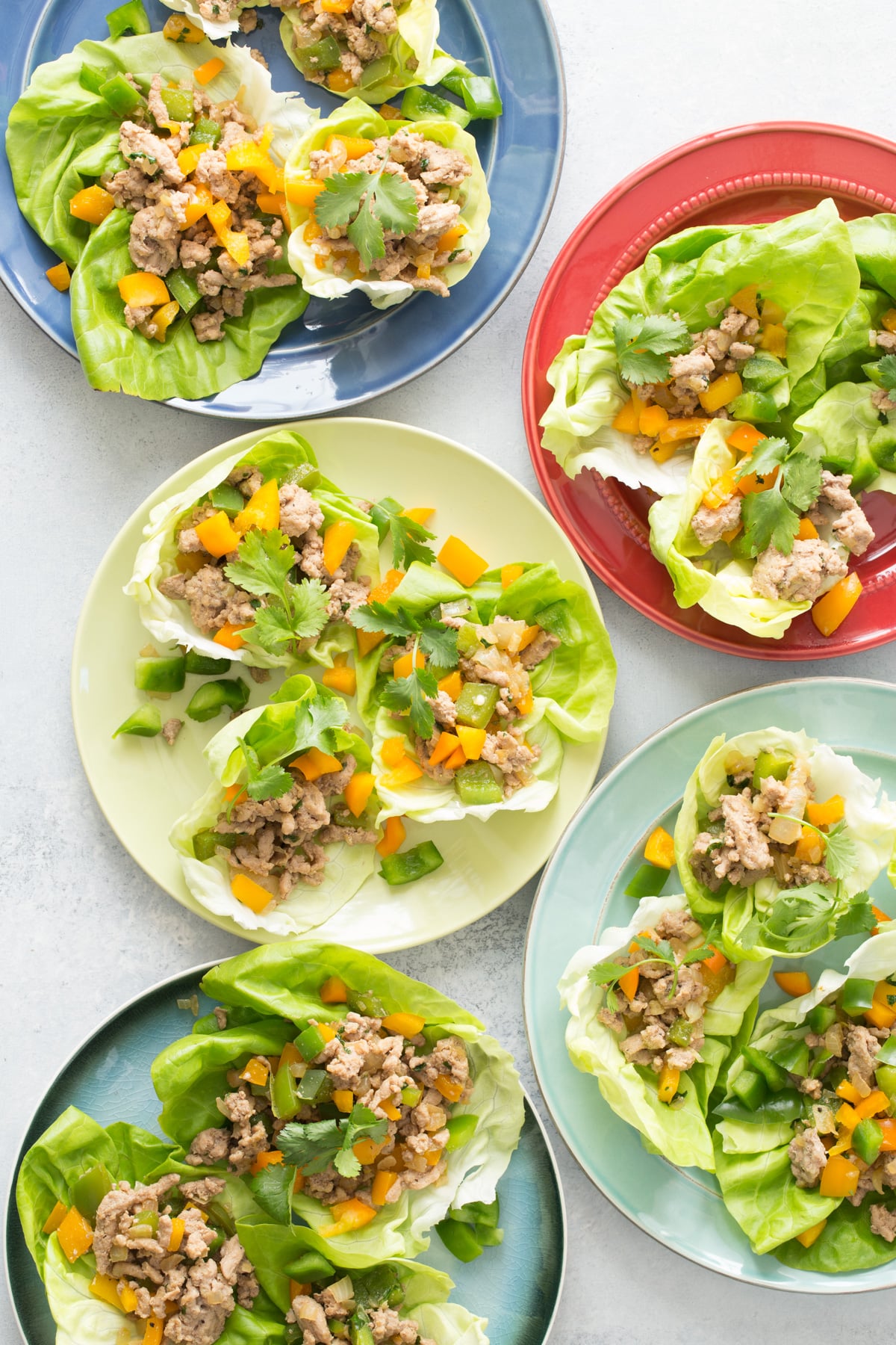 Stir-Fried Ground Chicken in Lettuce wraps on multicolor plates.